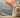 A hand holding a magnifying glass over a small burlap sack with a dollar sign on it. Next to the burlap sack is a small wooden gavel.